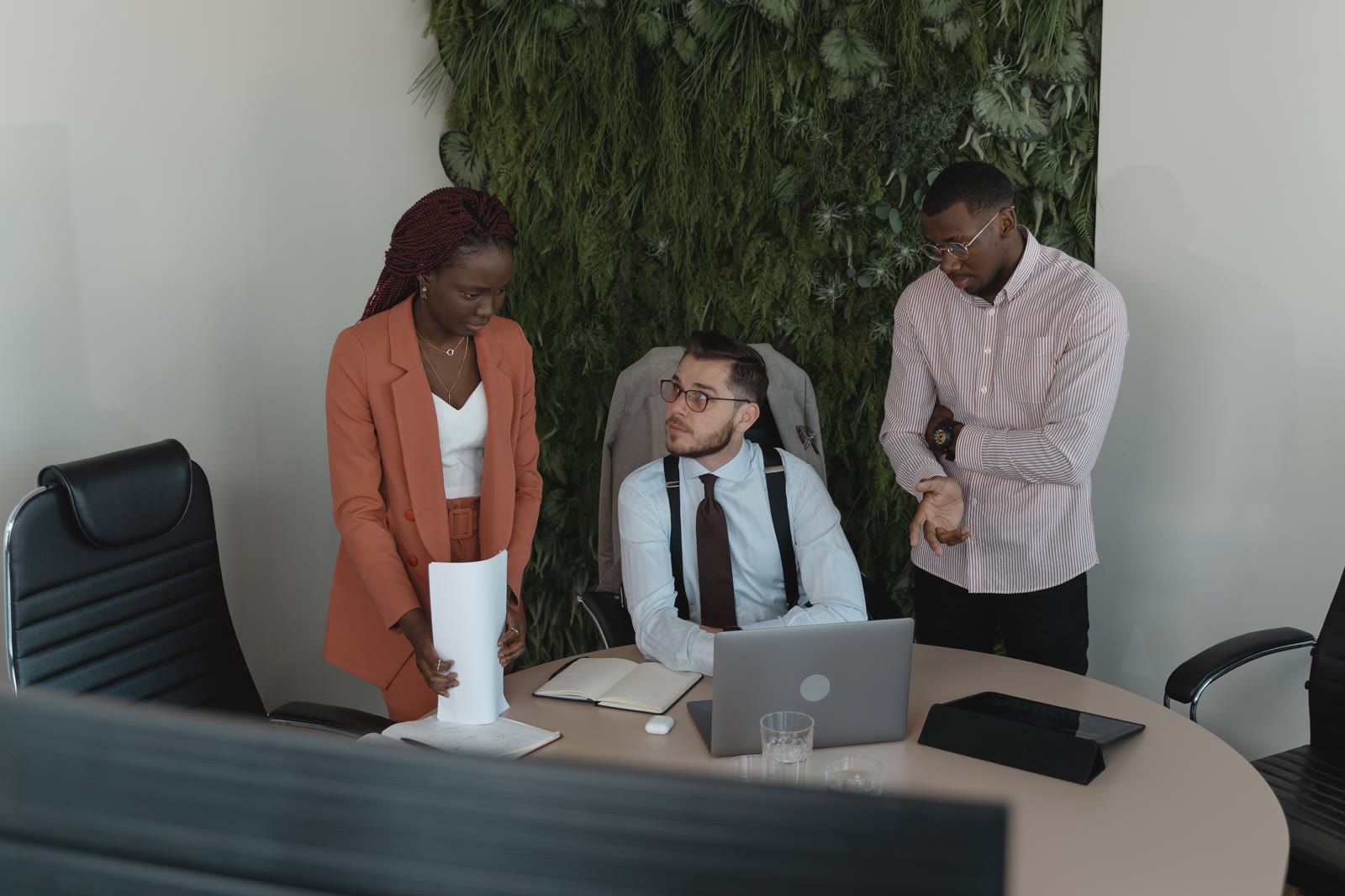 Three professionals gathered around a laptop in an office